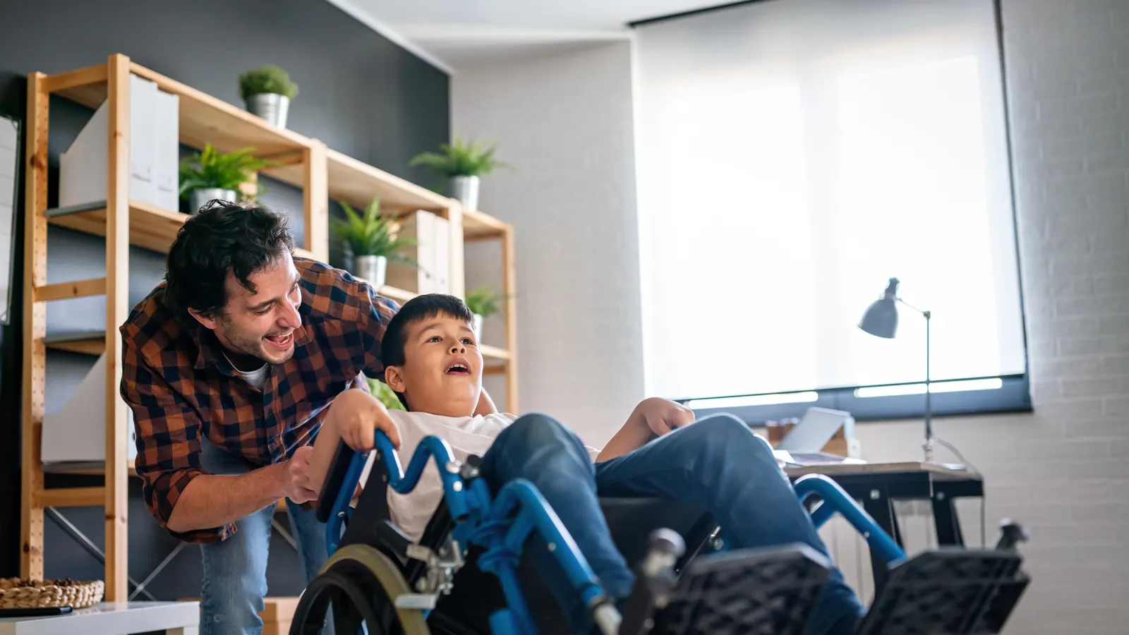 A man and a boy in a wheelchair playing together at home