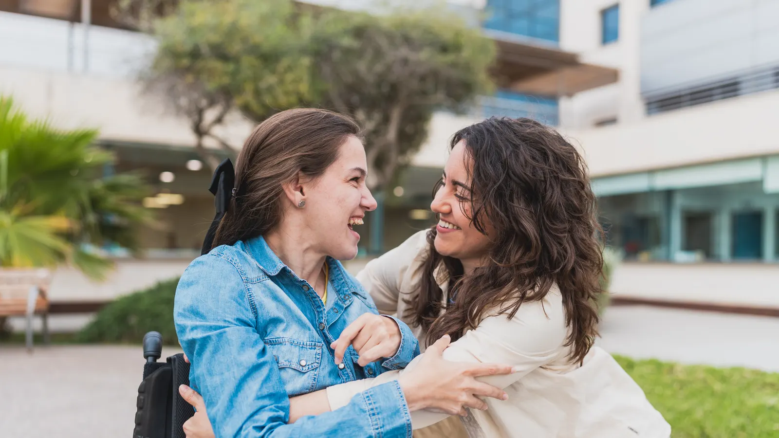 Two women embracing and smiling outdoors
